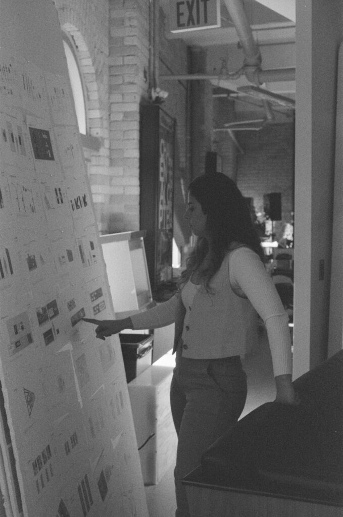 Black and white photo of Miranda, BMD graphic designer, working at the tall bulletin boards