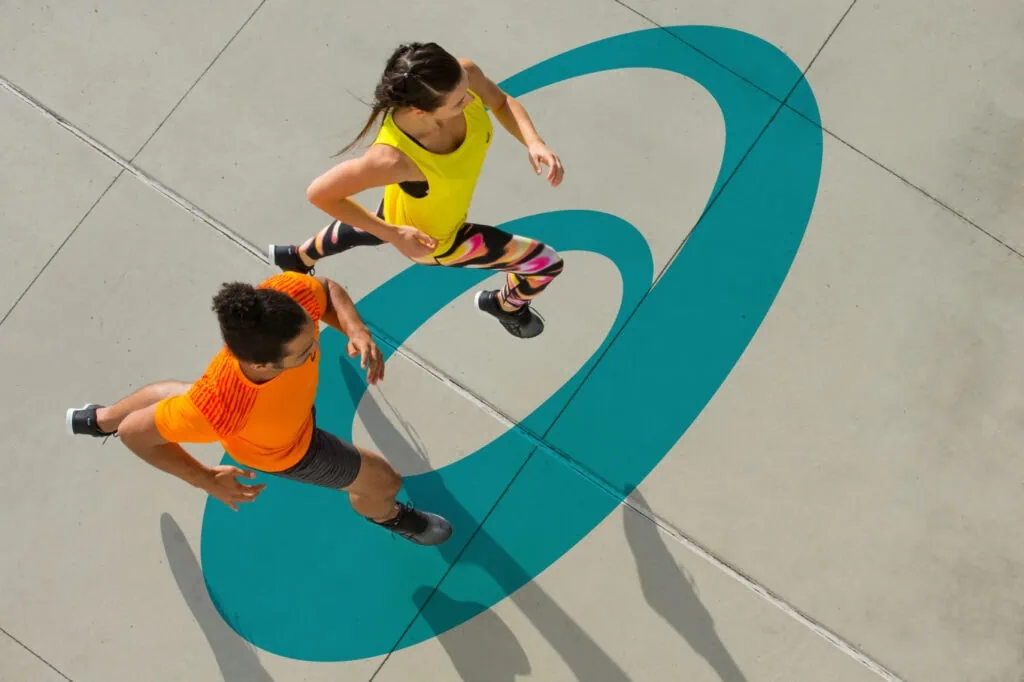 ASICS spiral logo on concrete with two runners above