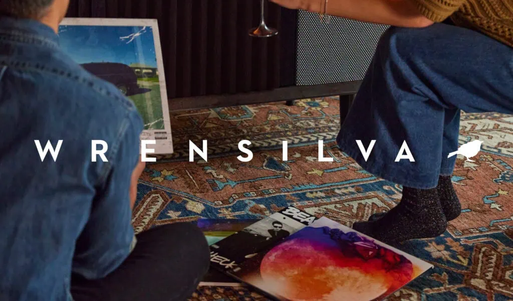 Two people sitting in front of a Wrensilva record console with the Wrensilva logo overtop