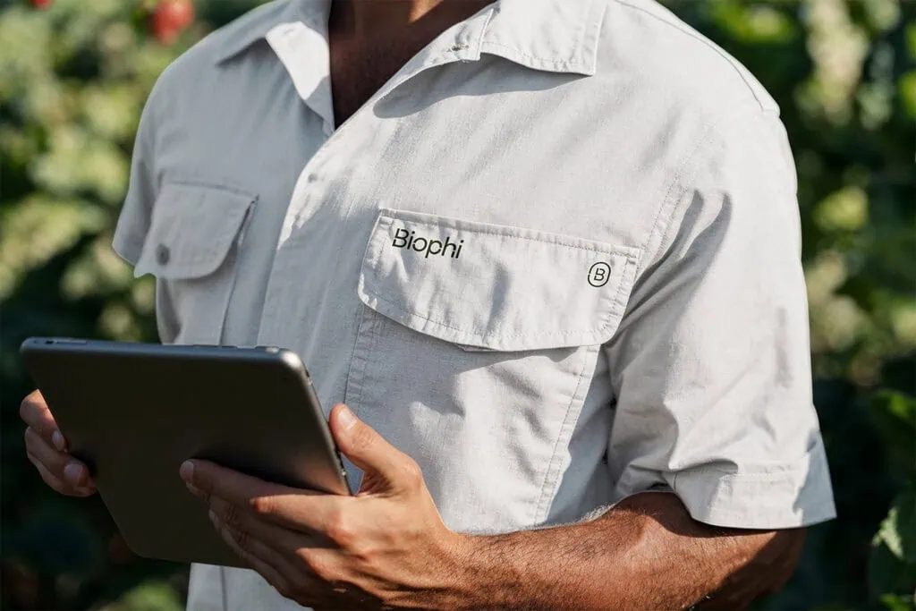 Closeup of a man wearing a white sleeveless shirt with the biophi logo on the right pocket.